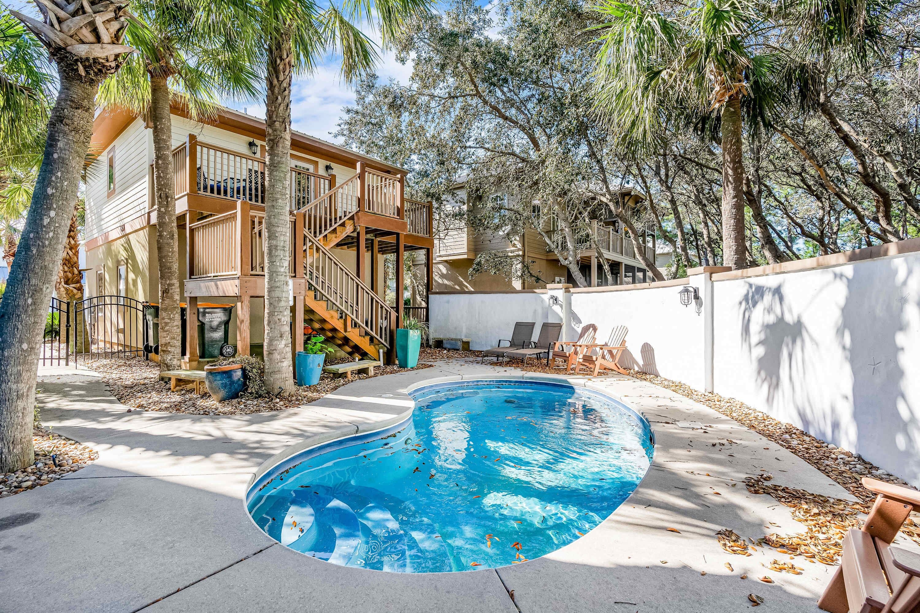 A residential area with a swimming pool, wooden deck, and a two-story house with a balcony.