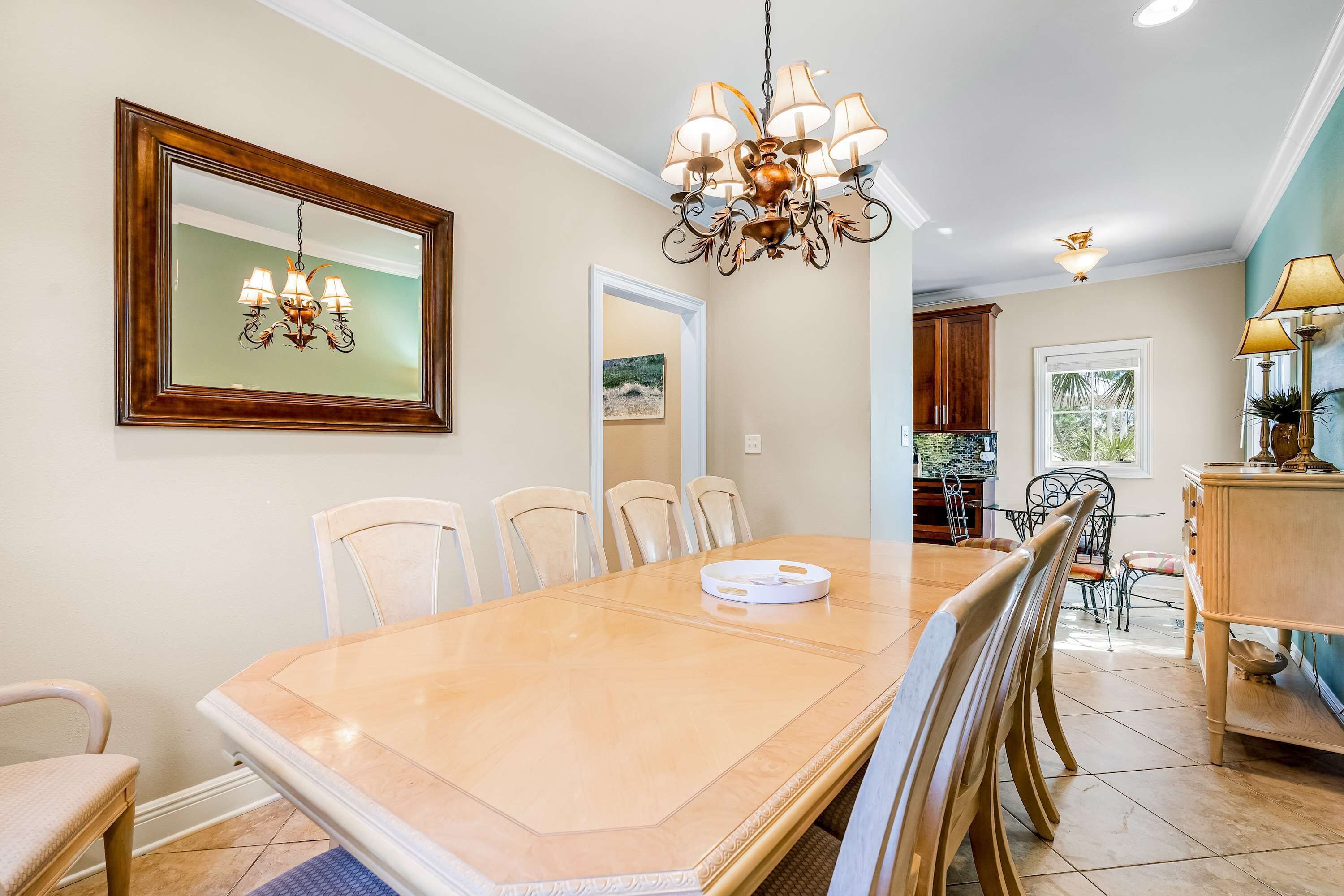 Un coin repas comprenant une grande table, des chaises, un lustre et un miroir au mur.