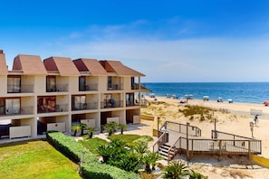 Een hotel aan het strand met meerdere balkons, een zandstrand en helder uitzicht op de oceaan.