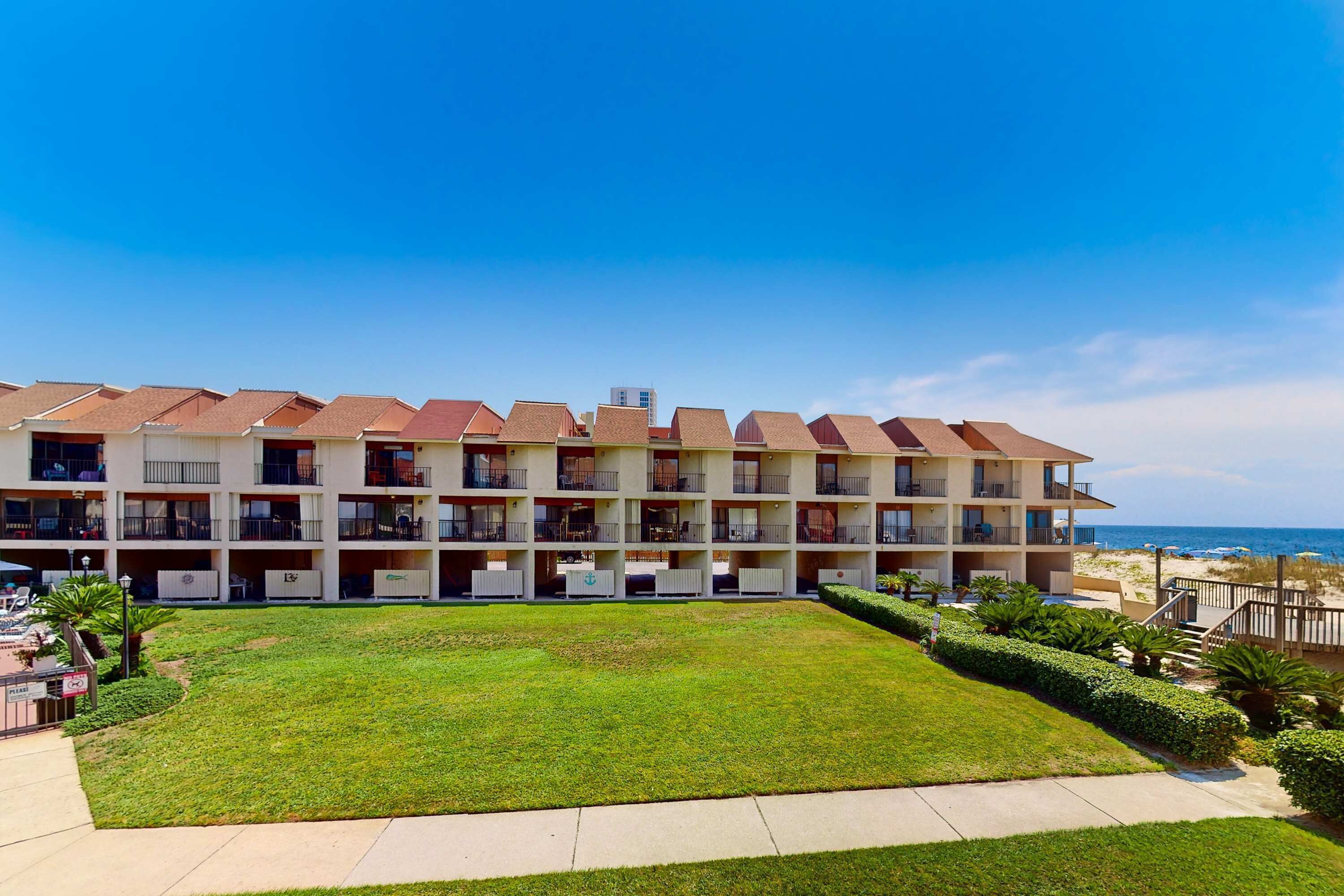 Ett hotell med flera våningar, balkonger, en grön innergård och utsikt över stranden.