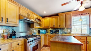 Una cucina con mobili in legno, piano cottura in acciaio inossidabile e un ripiano in granito.