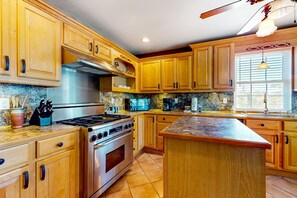 A kitchen with wooden cabinets, a stainless steel stove, and a granite countertop. - Sunny coastal hideaway with patio, large deck, W&D, & central AC (Gulf Shores)