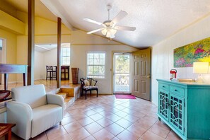 A spacious living room with a white sofa, a teal cabinet, and a ceiling fan. - Sunny coastal hideaway with patio, large deck, W&D, & central AC (Gulf Shores)