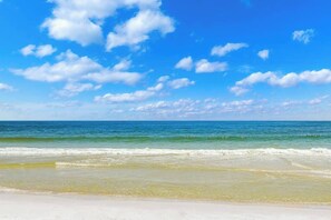 Uma praia com céu claro e águas calmas.