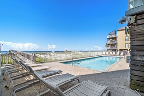 A pool area with lounge chairs and a view of the ocean. - Unique dog-friendly Gulf-front condo with amazing views, pools, sauna, gym, & AC (Gulf Shores)