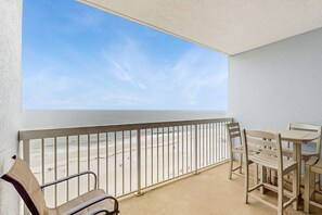 A balcony with a view of the beach, a table, and two chairs. - Unique dog-friendly Gulf-front condo with amazing views, pools, sauna, gym, & AC (Gulf Shores)