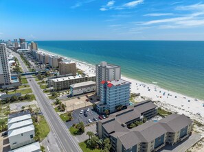 A coastal hotel with a beach view, multiple parking lots, and a clear sky. - Unique dog-friendly Gulf-front condo with amazing views, pools, sauna, gym, & AC (Gulf Shores)