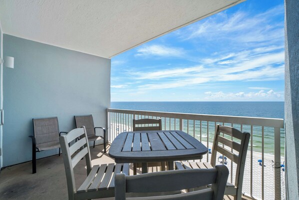 Een balkon met een tafel en stoelen, met uitzicht op de oceaan.