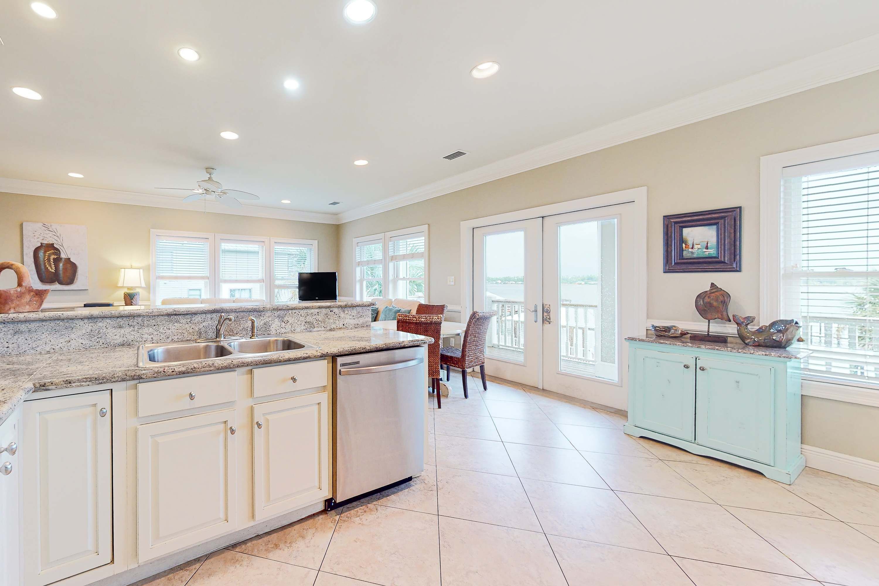 A spacious kitchen with a central island, white cabinetry, and a dining area with a view.