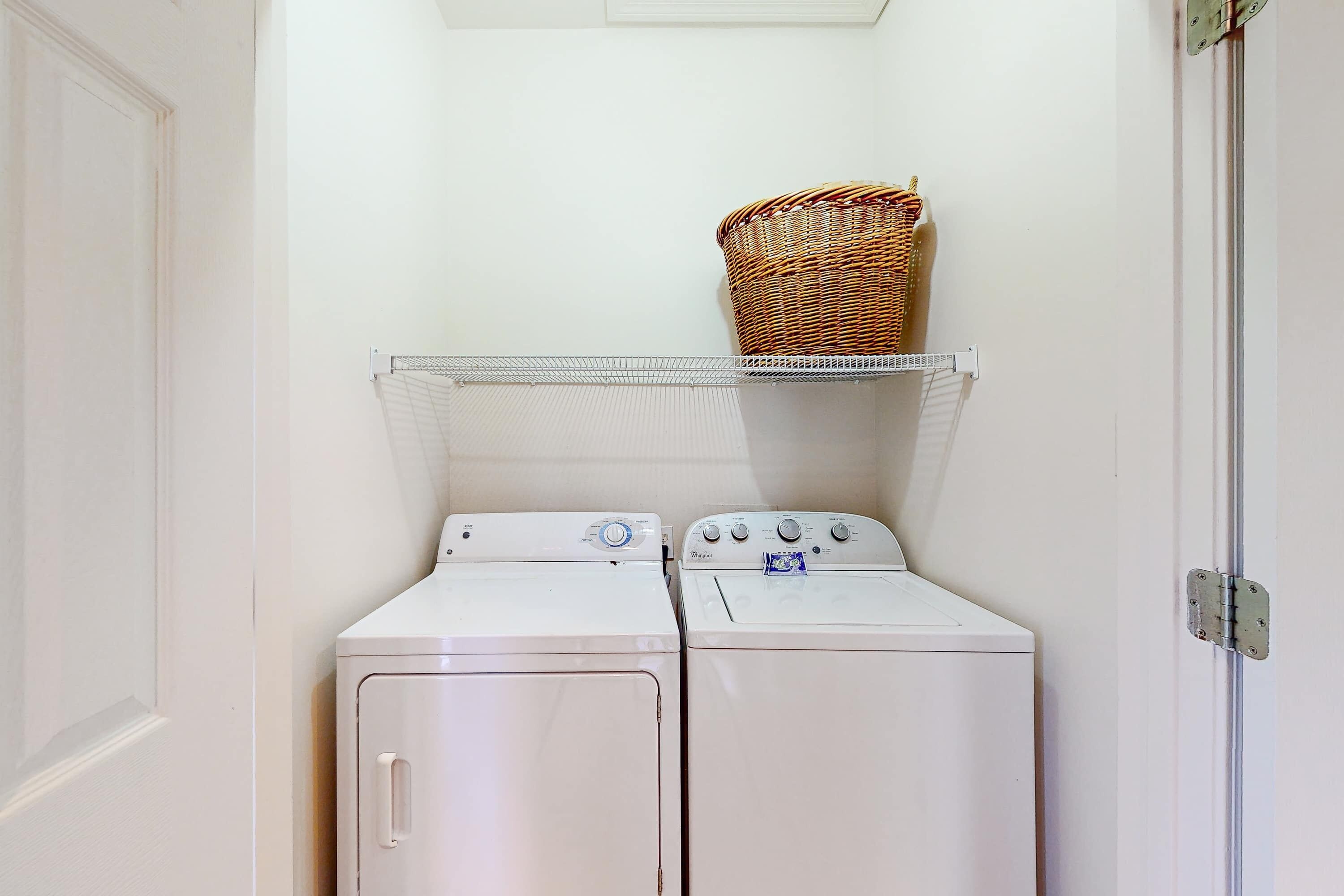 A laundry area with two white washing machines and a wicker basket on a shelf.
