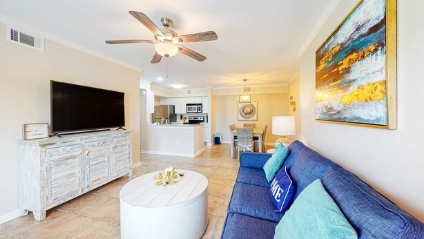 A living room with a TV, sofa, and ceiling fan. - Delightful coastal gem with pool, hot tub, private balcony, fast WiFi & AC (Gulf Shores)