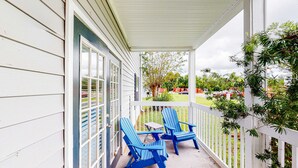 A porch with two blue Adirondack chairs and a small table. - Delightful coastal gem with pool, hot tub, private balcony, fast WiFi & AC (Gulf Shores)