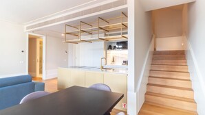 A modern apartment with a kitchen, dining area, and a staircase. - LovelyStay - Entreparedes House - 302 (Porto)