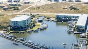 Un port de plaisance doté de plusieurs quais, un grand bâtiment à toit plat et un bâtiment plus petit à toit en pente.