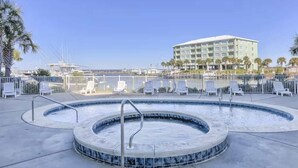Un bain à remous de forme circulaire, entouré de chaises longues, avec une marina et un hôtel en arrière-plan.