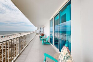 Een balkon met uitzicht op het strand, stoelen en een tafel.