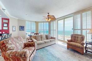 A living room with a sofa, armchair, and a ceiling fan. - Gulf-view condo with direct beach access, indoor & outdoor pools, hot tub, sauna (Gulf Shores)