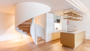 Eine moderne Küche mit einer zentralen Kochinsel, einer Wendeltreppe und eingebauten Schränken.