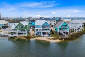 A coastal residential area with houses featuring balconies and waterfront views. - Remodeled, lagoon-front home with decks, views, paddleboat (Gulf Shores)