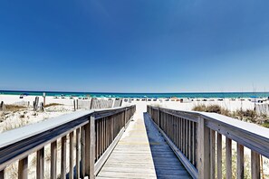 A wooden boardwalk leading to a beach with umbrellas and beachgoers. - Island Tower corner condo with infinity pool, two Balconies, & Gulf views (Gulf Shores)