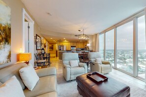 A spacious living area with a high ceiling, a dining area, and a kitchen. - Island Tower corner condo with infinity pool, two Balconies, & Gulf views (Gulf Shores)
