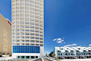 A modern hotel with a tall, cylindrical building and a beachfront property with light blue buildings. - Island Tower corner condo with infinity pool, two Balconies, & Gulf views (Gulf Shores)