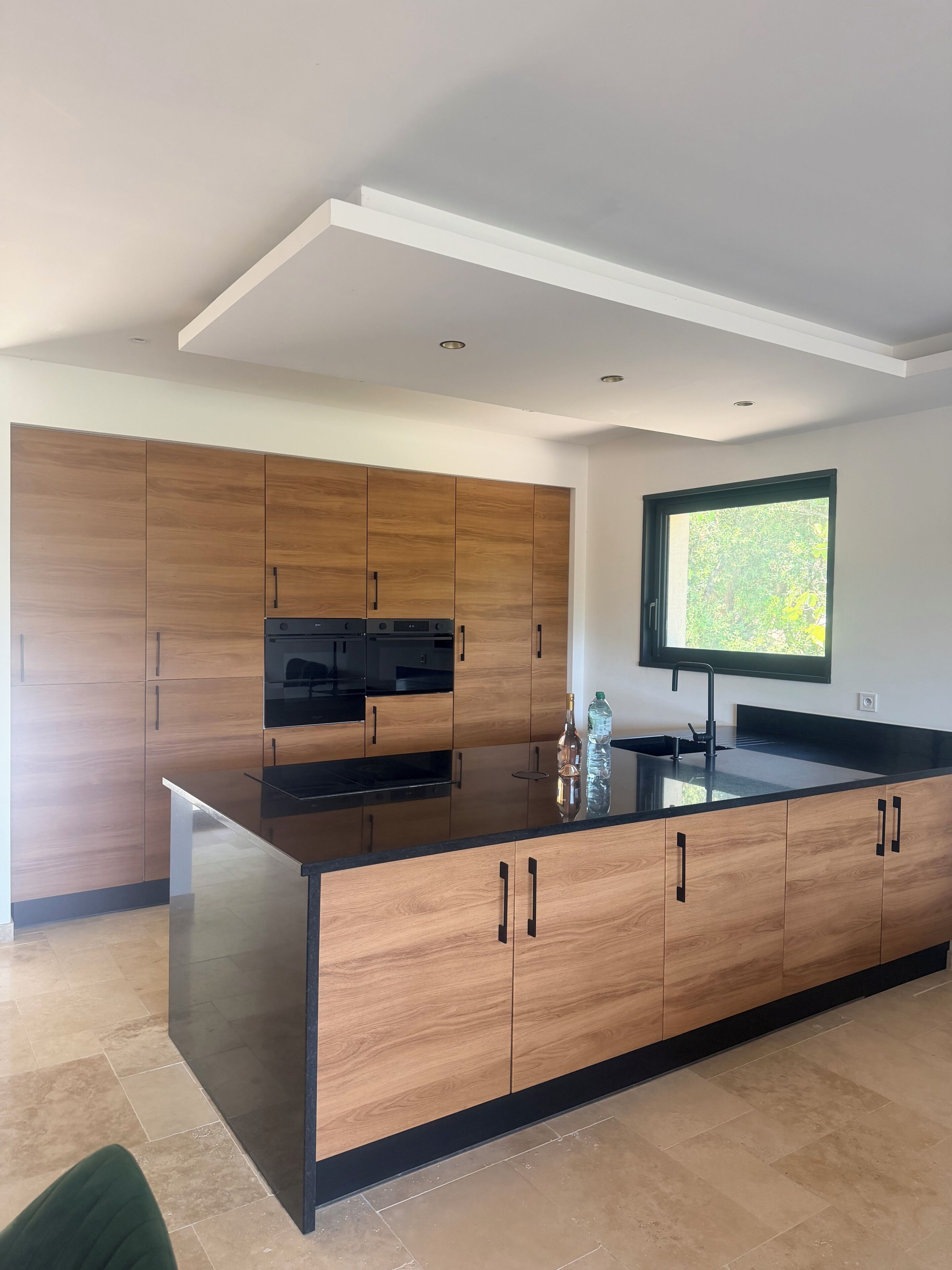 Una cucina moderna con mobili in legno, un piano di lavoro nero e una finestra con vista.