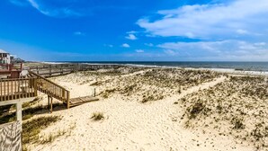 Ein Strand mit einer Holzpromenade, die zu einem Gebäude mit roter Brüstung führt.