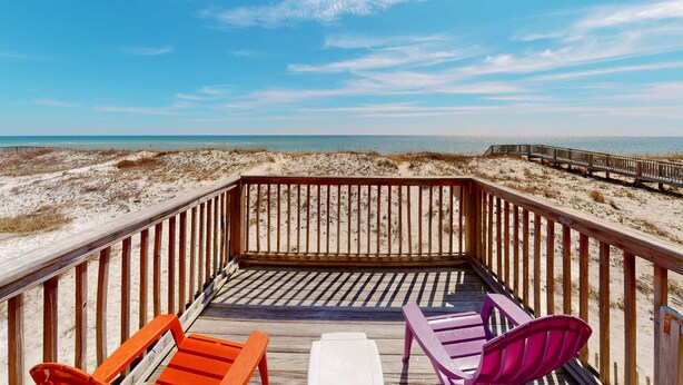 Eine Holzterrasse mit Blick auf Strand und Meer.