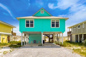 A turquoise two-story house with a covered porch, a small window, and a door. - Beachfront Home with Covered Deck, Gulf Views, Central AC, WiFi & Laundry (Gulf Shores)
