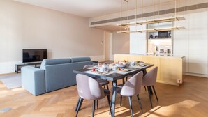 Ein modernes Wohnzimmer mit einer Couch, einem Esstisch, der für ein Frühstück gedeckt ist, und einer Küchenzeile mit einer Mikrowelle und einer Kaffeemaschine.