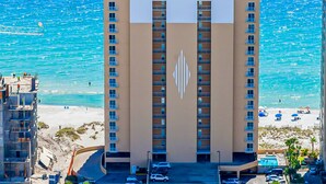 A high-rise hotel with a central atrium, multiple balconies, and a beach view. - Gulf-Front, 12th-Floor Condo w Great View, Balcony, AC & Shared Pools Hot Tubs (Gulf Shores)