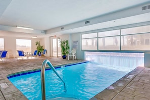 An indoor swimming pool with clear blue water, surrounded by lounge chairs and potted plants. - Gulf-Front, 12th-Floor Condo w Great View, Balcony, AC & Shared Pools Hot Tubs (Gulf Shores)