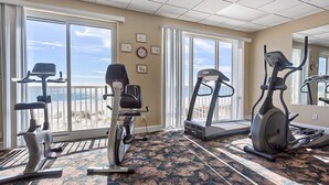 A gym with exercise equipment, large windows, and a carpeted floor. - Gulf-Front, 12th-Floor Condo w Great View, Balcony, AC & Shared Pools Hot Tubs (Gulf Shores)