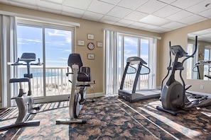 A gym with exercise equipment, large windows, and a carpeted floor. - Gulf-Front, 12th-Floor Condo w Great View, Balcony, AC & Shared Pools Hot Tubs (Gulf Shores)