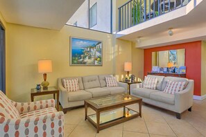 A living room with two sofas, a coffee table, and a painting on the wall. - Breezy Condo near the Beach w/Balcony, A/C, Shared Pool, Tennis, Hot Tub, WiFi (Gulf Shores)