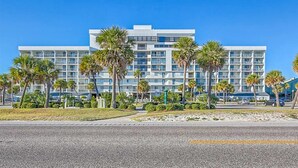 A multi-story hotel with a modern design, featuring balconies and a central courtyard with palm trees.