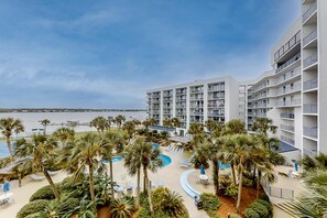 A hotel with multiple floors, a pool area with palm trees, and a view of the beach. - Breezy Condo near the Beach w/Balcony, A/C, Shared Pool, Tennis, Hot Tub, WiFi (Gulf Shores)