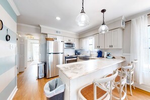 A modern kitchen with white cabinetry, stainless steel appliances, a marble island, and pendant lighting. - Gulf-Front Condo w Balcony, Beach Views, WiFi, AC & Shared Gulf-Facing Pool (Gulf Shores)
