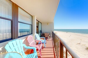 Ein Balkon mit Stühlen und einem Tisch, der Blick auf einen Strand bietet.