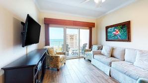 A living room with a flat-screen TV, a sofa, a chair, and a painting on the wall. - Gulf-view condo with pool, hot tub, lazy river & balcony (Gulf Shores)