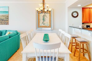 A dining area with a white table, chairs, and a green placemat. - Charming Ocean View Condo with Private Balcony, AC, Shared Outdoor Pool, Free WiFi (Gulf Shores)