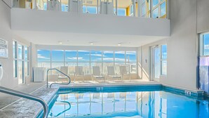 Ein Hallenbad mit klarem, blauen Wasser, einer Rettungswache und Blick auf die Stadt durch große Fenster.