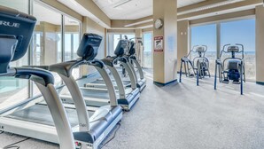 Ett gym med löpband, crosstrainers och en utsikt över staden genom stora fönster.