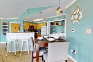A kitchen with a central island, bar stools, and a dining table with chairs. - Wonderful Family Retreat Near the Coast with Free WiFi & Shared Pool Hot Tub (Gulf Shores)