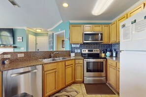 A modern kitchen with stainless steel appliances, wooden cabinets, and a tiled backsplash. - Wonderful Family Retreat Near the Coast with Free WiFi & Shared Pool Hot Tub (Gulf Shores)