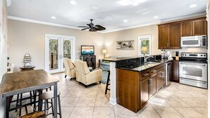 Una cocina moderna con una isla central, un comedor con mesa de madera y una sala de estar con sofá y sillones.