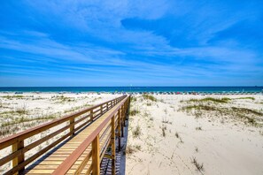A wooden boardwalk leading to a beach with sand dunes and a clear blue sky. - 3rd-floor Gulf-view condo with hot tub, outdoor pool, tennis, balcony, elevator (Gulf Shores)