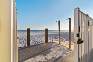 Une terrasse en bois qui mène à une plage, avec un ciel dégagé.