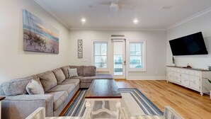 Ein Wohnzimmer mit Ecksofa, Couchtisch, Flachbildfernseher und einem Gemälde an der Wand.